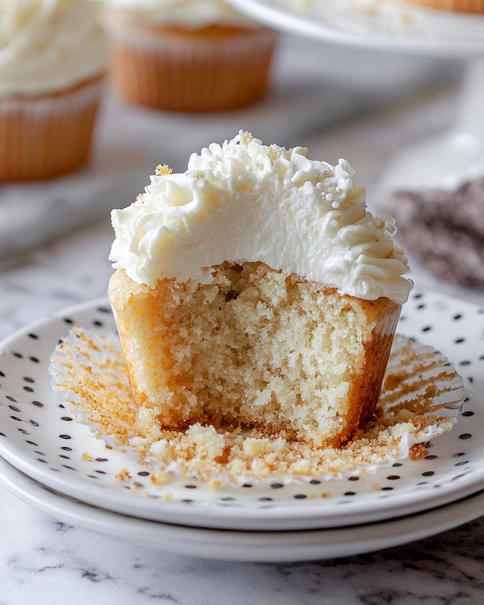 White Cupcakes with Whipped Cream Cheese Frosting Recipe 4 A full white cupcake stand showcasing an array of perfectly baked white cupcakes each topped with generous swirls of creamy white frosting sprinkled with clear sugar crystals, arranged neatly and uniformly, shot at a 3/4 angle with a crisp white marble background, natural lighting highlighting the smooth texture of the frosting and the soft crumb of the cupcakes, professional food magazine hero-style photo taken with an iphone --ar 4:5 --v 7