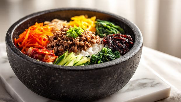 A white plate holds a dish with three main layers. On the right side is a scoop of white steamed rice with a soft texture. Next to the rice is a ground meat mixture, browned and cooked with green leafy vegetables and bright red chili pieces, sprinkled with white and black sesame seeds, with a slightly glossy sauce coating the meat. On the top-left corner of the plate, a perfectly cooked sunny-side-up egg sits with a bright yellow yolk and white edges slightly crisp. The plate is on a white marbled surface. Photo taken with an iphone --ar 4:5 --v 7