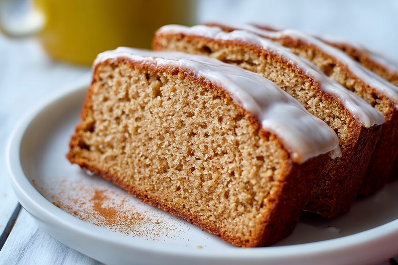 Whole rectangular loaf of moist banana bread topped with a smooth layer of creamy light brown frosting covering the entire top surface, placed on a large white ceramic platter, photographed from a 3/4 angle to show the entire uncut loaf, styled for an elegant food magazine hero shot on a white marble kitchen countertop with natural soft directional daylight streaming near windows, emphasizing the texture and rich color of the bread and frosting, garnished simply for a luxurious and indulgent presentation. REALISTIC STYLE IMAGE| TAGS: High-end food photography, clean composition, dramatic lighting, luxurious, elegant, mouth-watering, indulgent, gourmet | CAMERA: Nikon Z7 | FOCAL LENGTH: 50mm | SHOT TYPE: Close-up | COMPOSITION: 3/4 angle | LIGHTING: Soft directional light | PRODUCTION: Food Stylist | TIME: Daytime I LOCATION TYPE: Kitchen near windows --stylize 150 --ar 3:2
