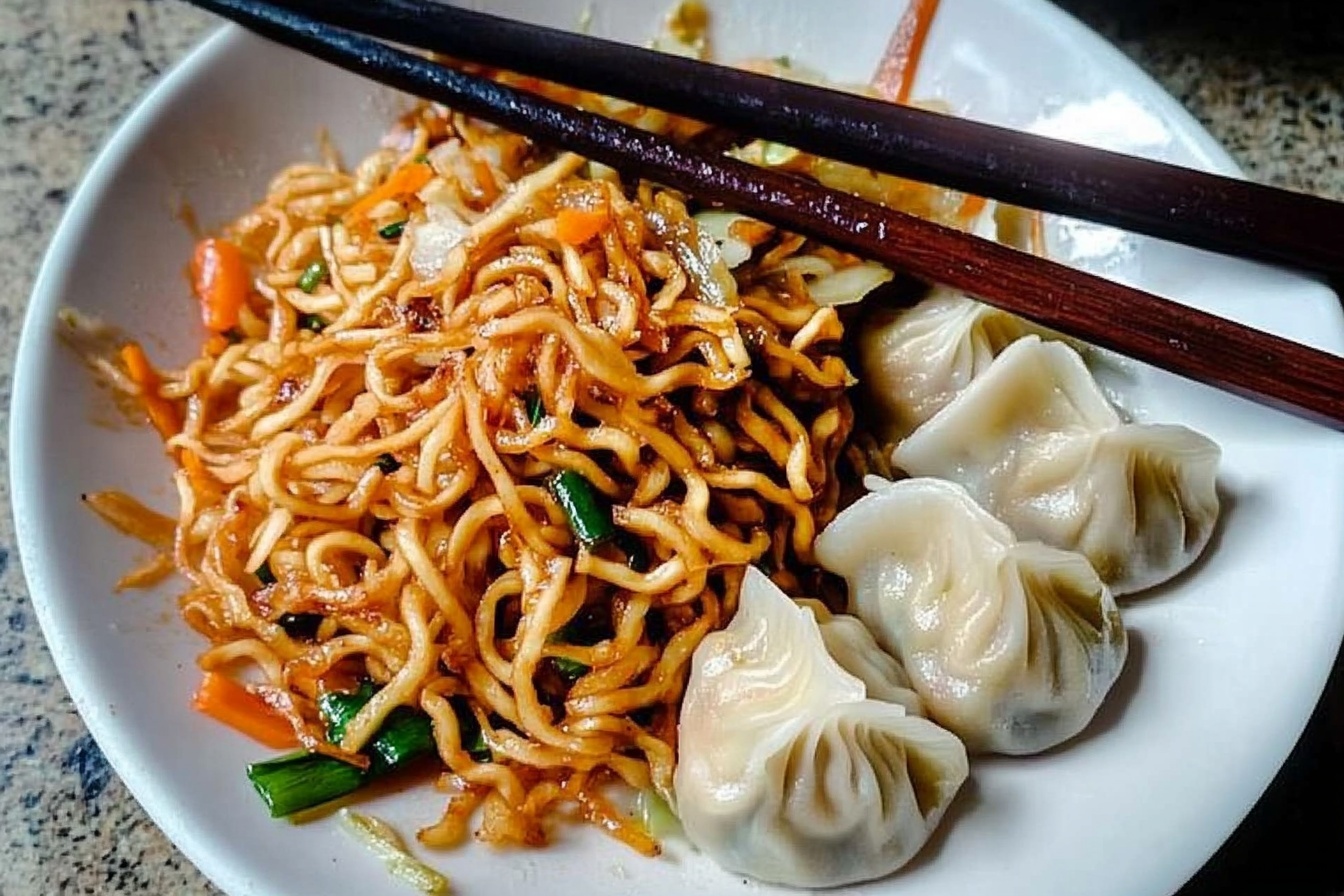 Chow Mein Noodles with Dumplings Recipe 6 A large white ceramic plate heaped with a generous serving of golden-brown vegetable fried noodles interspersed with sliced green bell peppers, shredded cabbage, and finely chopped carrots, glistening with a light savory sauce, accompanied by a neat row of six plump, steamed dumplings with smooth, slightly translucent wrappers, showcasing their beautifully pleated edges. The complete dish is presented on a white marble surface, shot from a 3/4 angle in natural daylight, styled with precision to highlight the textures and vibrant colors, evoking an inviting and indulgent homemade meal. REALISTIC STYLE IMAGE| TAGS: High-end food photography, clean composition, dramatic lighting, luxurious, elegant, mouth-watering, indulgent, gourmet | CAMERA: Nikon Z7 | FOCAL LENGTH: 50mm | SHOT TYPE: Close-up | COMPOSITION: 3/4 angle | LIGHTING: Soft directional light | PRODUCTION: Food Stylist | TIME: Daytime I LOCATION TYPE: Kitchen near windows --stylize 150 --ar 3:2